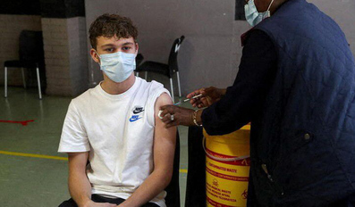 A healthcare worker administers a dose of the Pfizer coronavirus vaccine to a teenager
